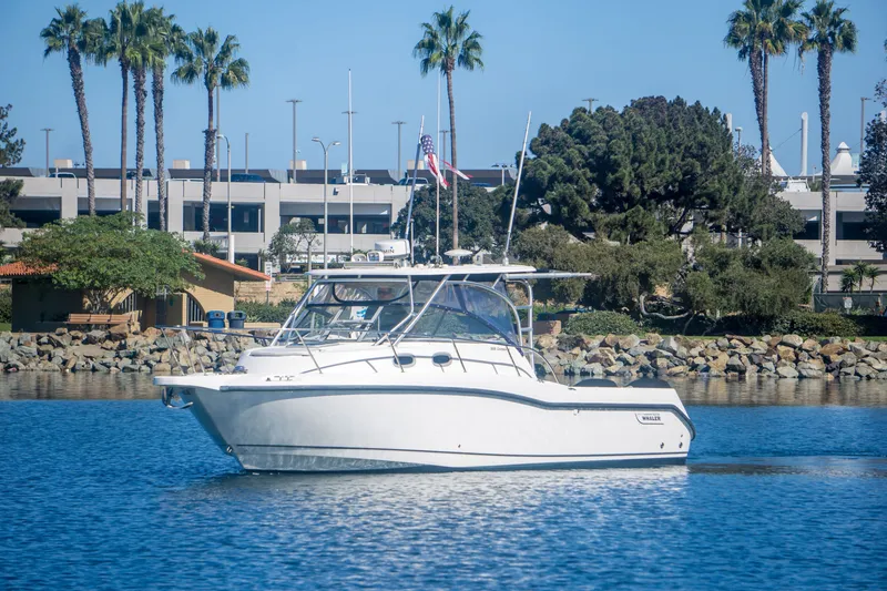 Slide: The Image of 2005 Boston Whaler 305 Conquest boat on calm water near a marina with palm trees. - 3