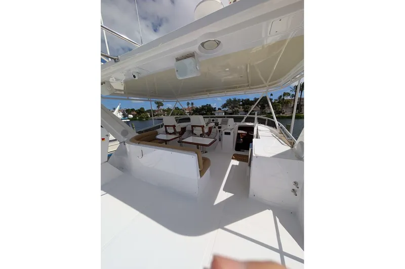 Slide: The Image of 1998 Offshore Yachts 54 Pilot House deck with seating and helm, under sunny skies. - 14