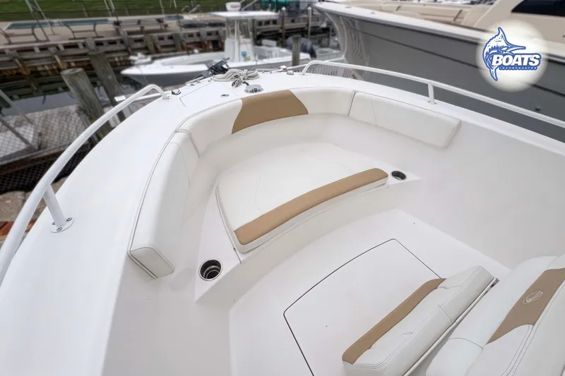 Slide: The Image of 2021 Edgewater 208CC boat interior with white and tan seating at a marina. - 4