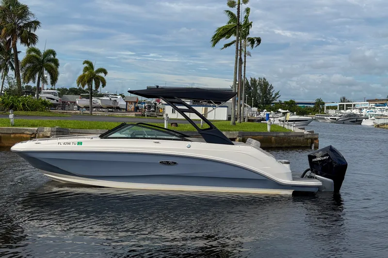 Slide: The Image of 2024 Sea Ray SDX 250 boat docked on a calm waterway with palm trees. - 4