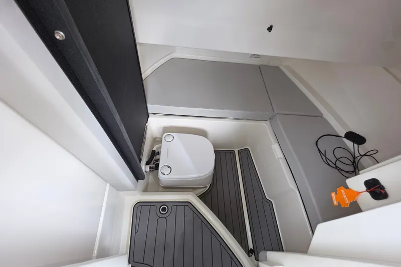 Slide: The Image of 2024 Sea Ray SDX 250 interior cabin with compact toilet and seating area. - 11