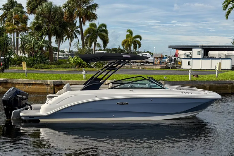 Slide: The Image of 2024 Sea Ray SDX 250 boat docked by palm trees, featuring sleek design and Mercury outboard engine. - 2