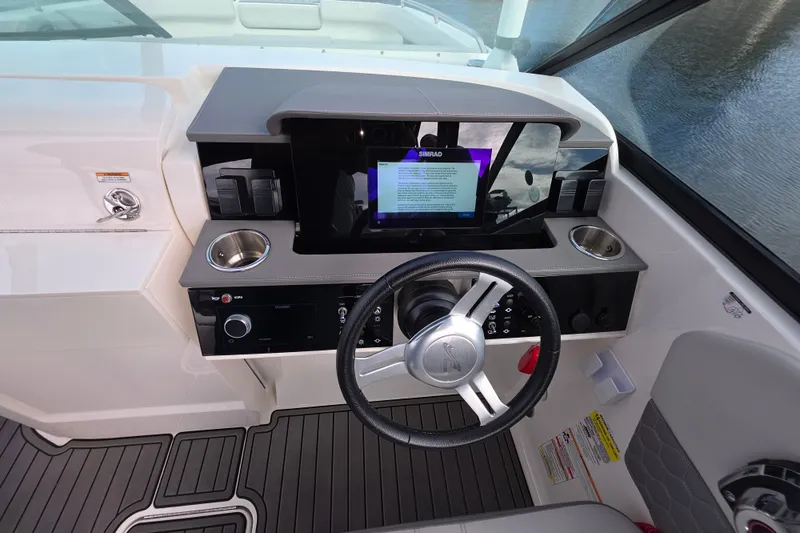Slide: The Image of 2024 Sea Ray SDX 250 helm with steering wheel, touchscreen display, and cup holders. - 13