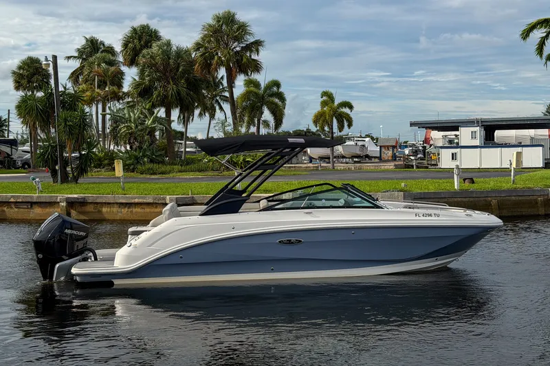 The Image of 2024 Sea Ray SDX 250 boat docked on a calm waterway with palm trees in the background. - 1