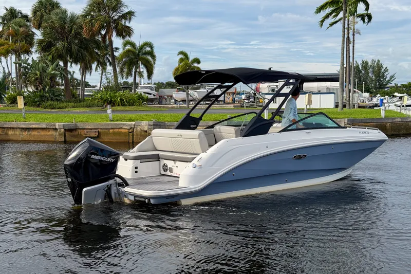 Slide: The Image of 2024 Sea Ray SDX 250 boat cruising on a calm waterway with lush greenery. - 5