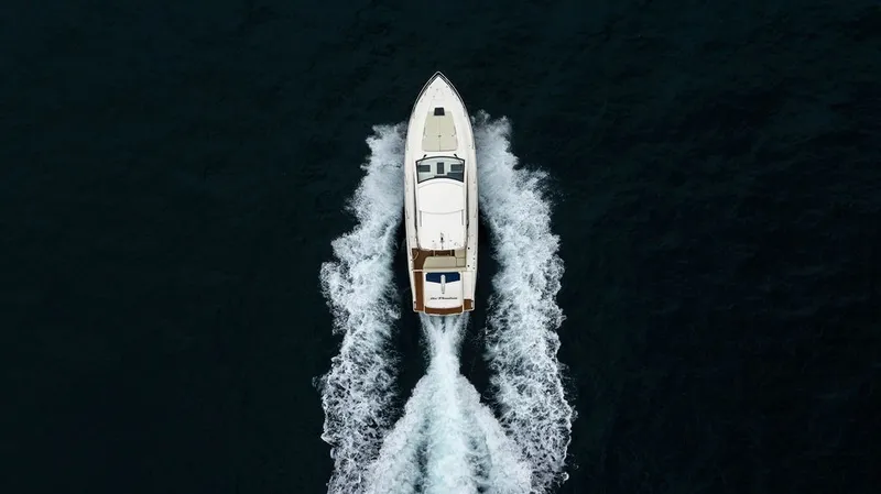 Slide: The Image of Aerial view of a white motor yacht cruising through dark water, leaving a distinct wake. - 23