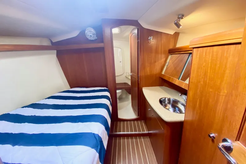 Slide: The Image of Interior of 2008 Hunter 41 Aft Cockpit yacht with cozy cabin and striped bedding. - 29