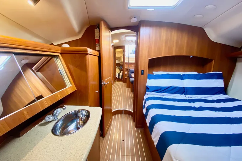 Slide: The Image of Luxurious interior of 2008 Hunter 41 Aft Cockpit yacht with striped bedding and wooden finishes. - 33