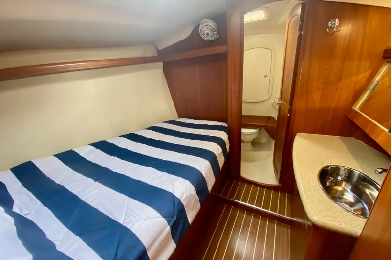 Slide: The Image of 2008 Hunter 41 Aft Cockpit cabin with striped bedding and ensuite bathroom. - 28