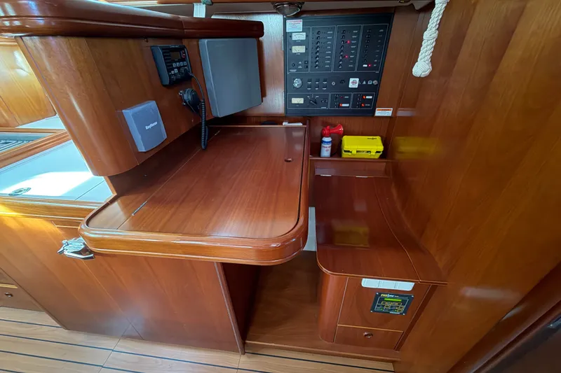 Slide: The Image of Interior of a 2001 Beneteau 50 yacht featuring a wooden navigation station and control panel. - 8