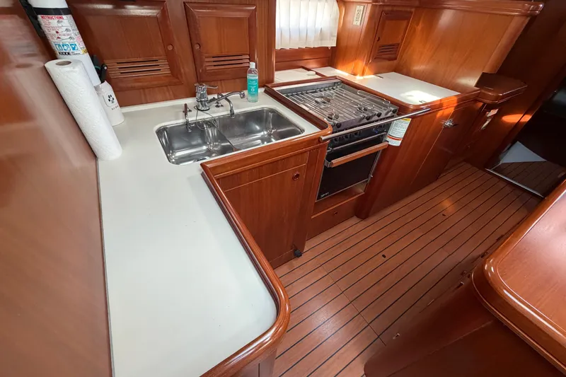 Slide: The Image of Galley kitchen in 2001 Beneteau 50 yacht with wood finish and stainless steel sink. - 10