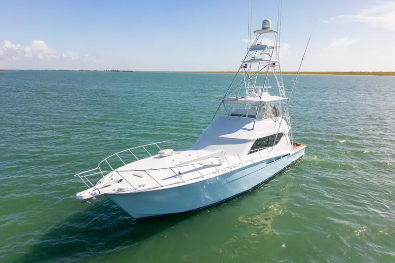 The Image of 2005 Hatteras 60 Convertible yacht cruising on open water under clear skies. - 0