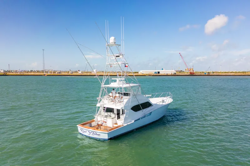 Slide: The Image of 2005 Hatteras 60 Convertible yacht on calm waters, clear sky, industrial background. - 3