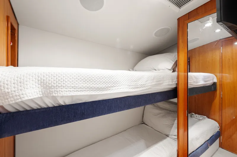 Slide: The Image of Bunk beds in 2005 Hatteras 60 Convertible yacht cabin, featuring wooden accents and white bedding. - 17