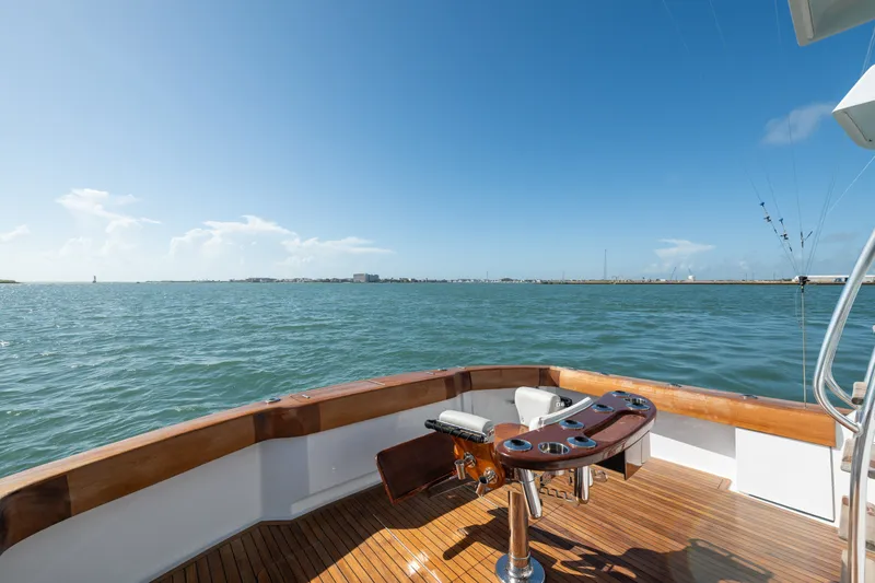 Slide: The Image of 2005 Hatteras 60 Convertible yacht deck with fishing chair, overlooking calm ocean waters. - 42