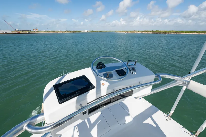 Slide: The Image of Helm of 2005 Hatteras 60 Convertible yacht overlooking serene waters. - 36