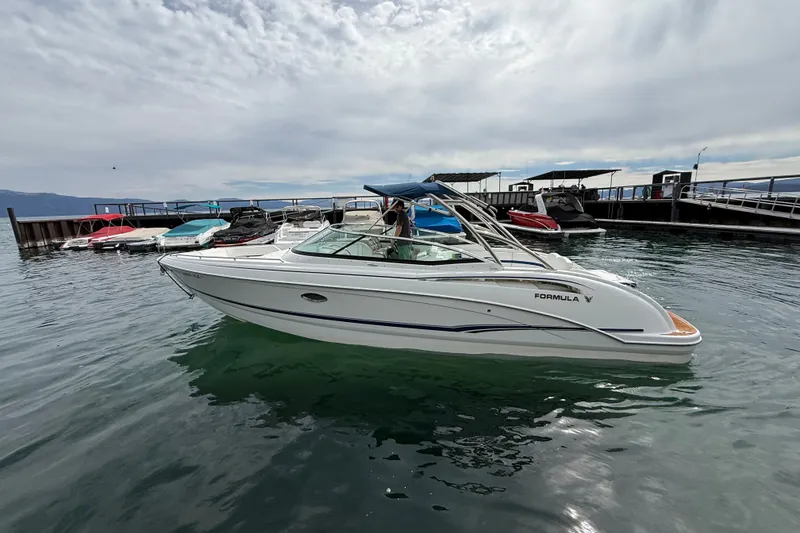 Slide: The Image of 2008 Formula 310 Bowrider boat docked on calm water under cloudy sky. - 2