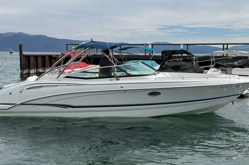 The Image of 2008 Formula 310 Bowrider boat docked on a serene lake with mountains in the background. - 0