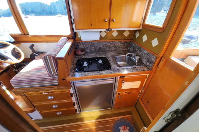 Slide: The Image of Compact 1974 custom boat kitchen with stove, sink, and striped seating. - 7