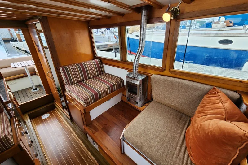 Slide: The Image of Cozy 1974 custom launch interior with striped seating, wood paneling, and a compact stove. - 3