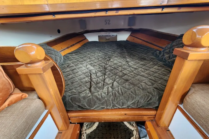 Slide: The Image of Cozy cabin interior of a 1974 Custom Launch with a quilted bed and wooden accents. - 8