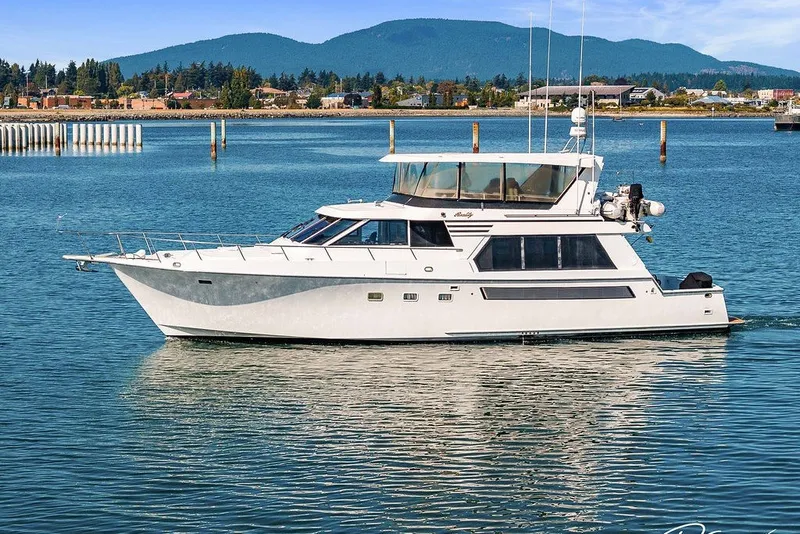 Slide: The Image of 1993 Tollycraft 57 Pilothouse Motor Yacht cruising on calm waters with scenic backdrop. - 54