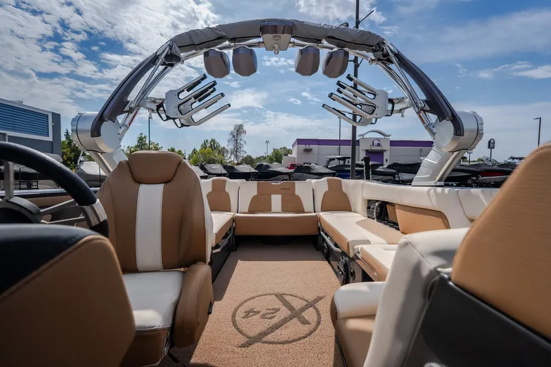 Slide: The Image of 2021 MasterCraft X24 boat interior with tan and white seating, under a clear sky. - 41