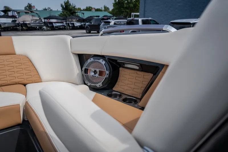 Slide: The Image of 2021 MasterCraft X24 boat interior with tan and white seating, speaker, and cup holders. - 37