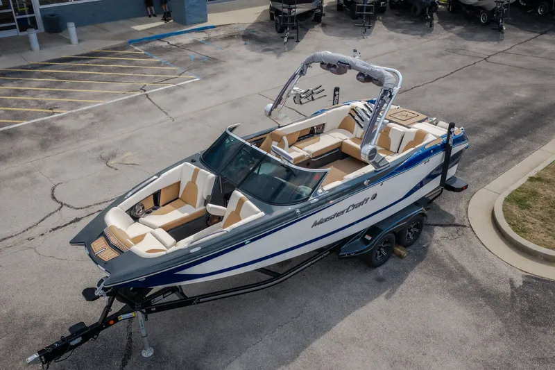 Slide: The Image of 2021 MasterCraft X24 boat on trailer, parked in a lot, showcasing sleek design and spacious interior. - 57