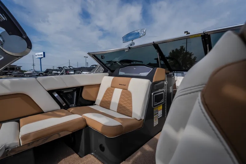 Slide: The Image of 2021 MasterCraft X24 boat interior with tan and white seating under a blue sky. - 29