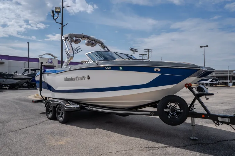 The Image of 2021 MasterCraft X24 boat on trailer in parking lot under cloudy sky. - 0