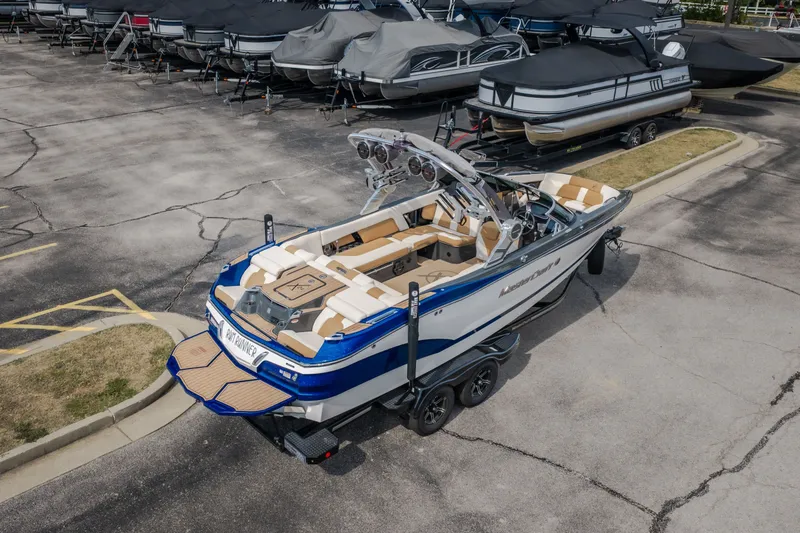 Slide: The Image of 2021 MasterCraft X24 boat in a parking lot, surrounded by covered boats. - 54