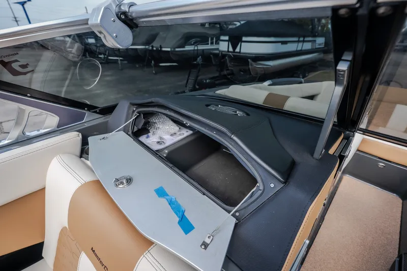 Slide: The Image of 2021 MasterCraft X24 boat interior with open storage compartment and beige seating. - 34