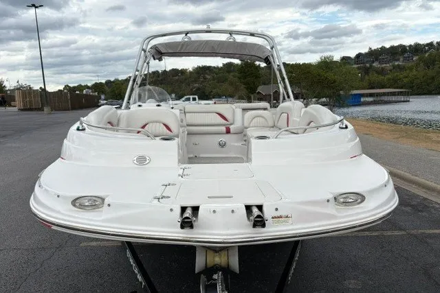 Slide: The Image of 2012 Starcraft 2000 IO Limited boat, white exterior, parked near a lake under cloudy skies. - 23