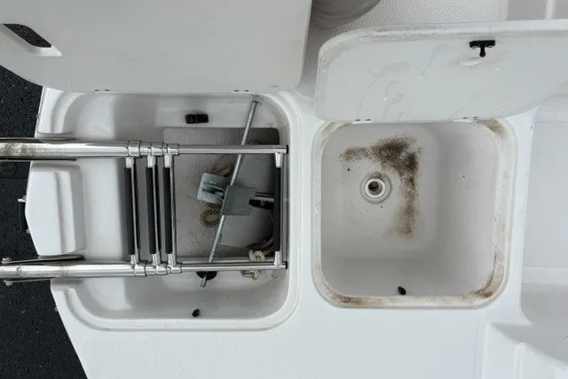 Slide: The Image of 2012 Starcraft 2000 IO Limited boat storage compartments with ladder and drain. - 21
