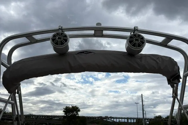 Slide: The Image of Bimini top and speakers on a 2012 Starcraft 2000 IO Limited boat under cloudy sky. - 26