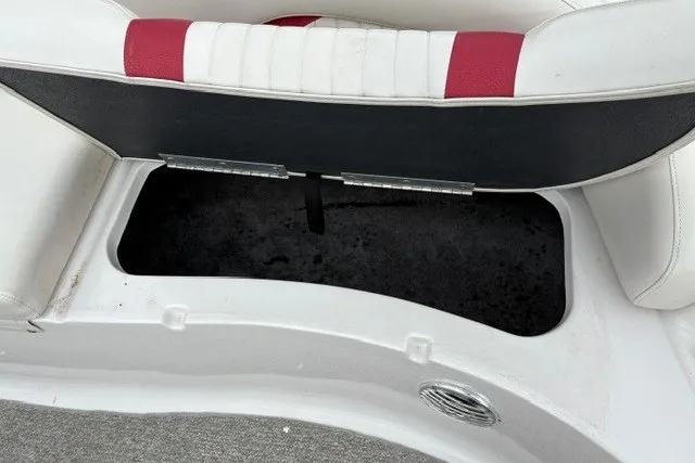 Slide: The Image of Open storage compartment in a 2012 Starcraft 2000 IO Limited boat with red and white seating. - 18