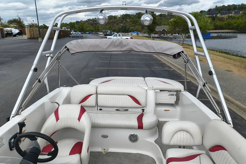 Slide: The Image of 2012 Starcraft 2000 IO Limited boat interior with white and red seating, parked near a lake. - 40