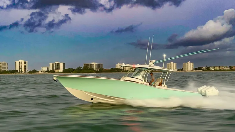 Slide: The Image of 2025 Mag Bay 38 CC boat cruising on water at sunset near city skyline. - 1