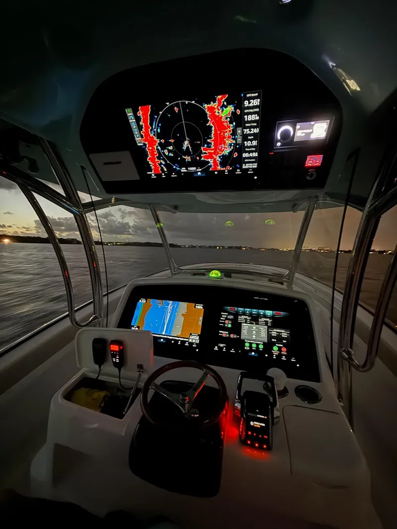 Slide: The Image of 2025 Mag Bay 38 CC boat cockpit with illuminated navigation screens at dusk. - 10