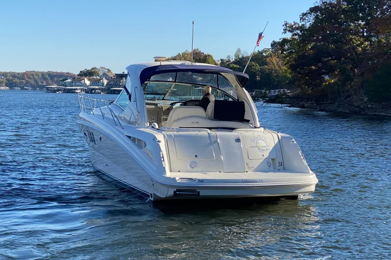 Slide: The Image of 2006 Sea Ray 38 Sundancer yacht cruising on a serene lake with scenic background. - 4
