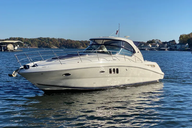 Slide: The Image of 2006 Sea Ray 38 Sundancer yacht on a serene lake under clear blue skies. - 2