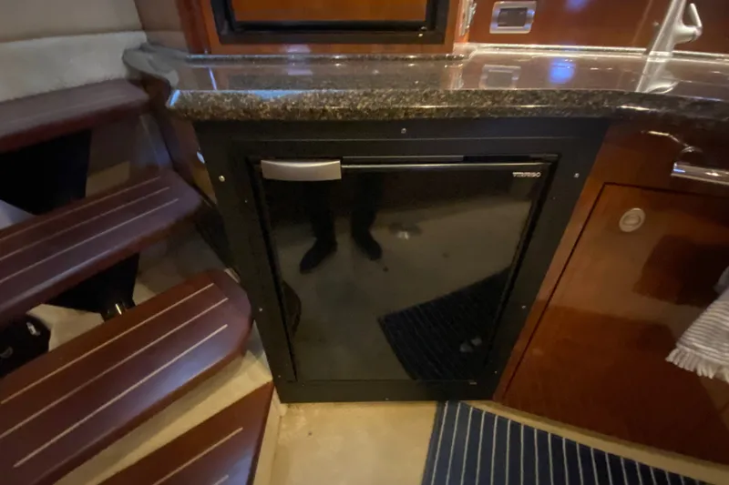 Slide: The Image of Interior of 2006 Sea Ray 38 Sundancer with compact fridge and wooden steps. - 23