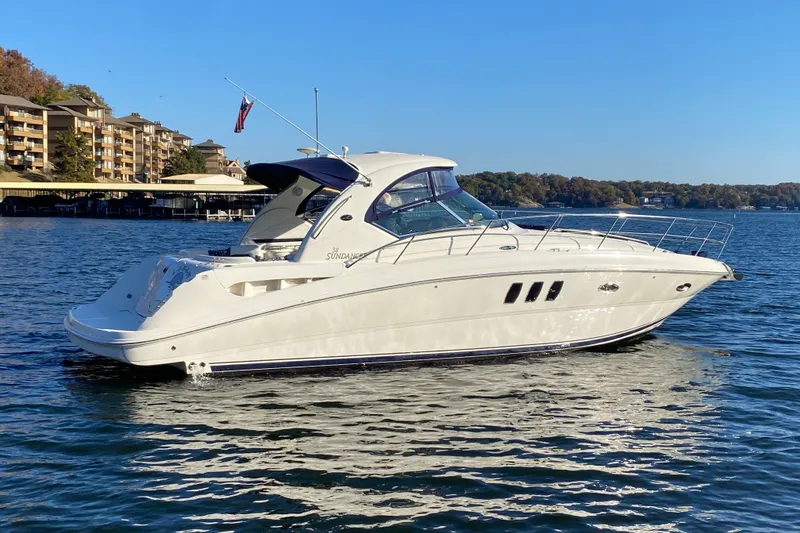 Slide: The Image of 2006 Sea Ray 38 Sundancer yacht cruising on a serene lake with clear blue skies. - 6