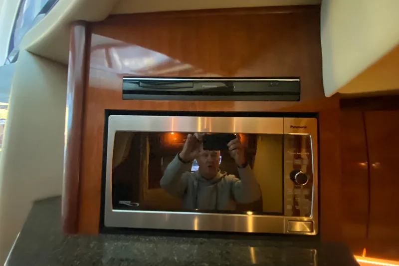 Slide: The Image of 2006 Sea Ray 38 Sundancer interior with Panasonic microwave and wood paneling. - 26