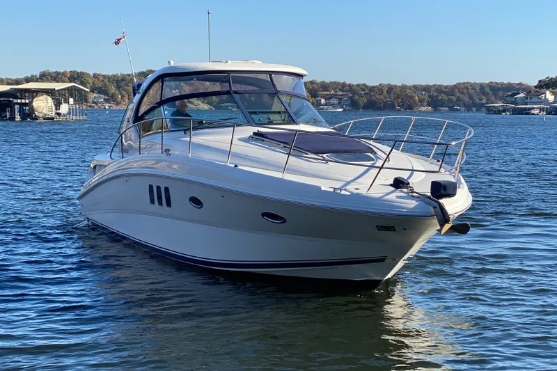 Slide: The Image of 2006 Sea Ray 38 Sundancer yacht on a serene lake with clear blue skies. - 4