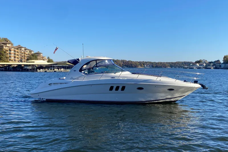 Slide: The Image of 2006 Sea Ray 38 Sundancer yacht cruising on a serene lake under a clear blue sky. - 5