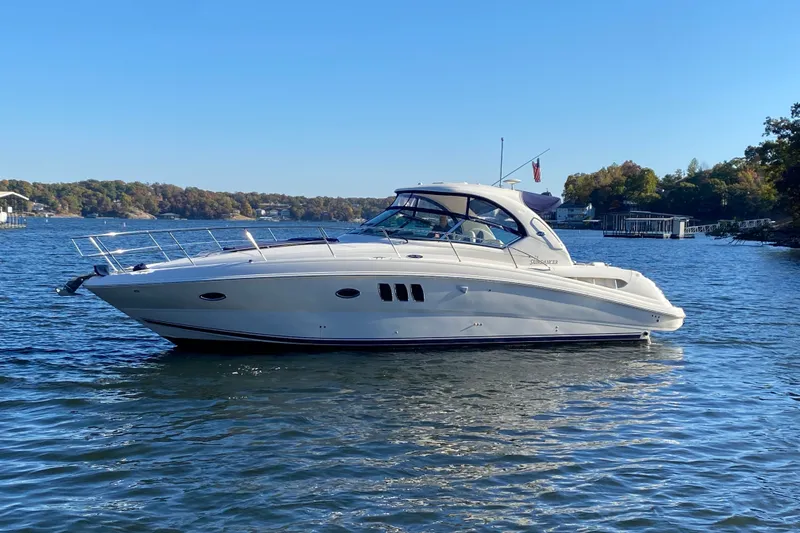 Slide: The Image of 2006 Sea Ray 38 Sundancer yacht on a serene lake with clear blue skies. - 5