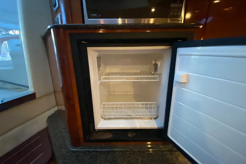 Slide: The Image of Open refrigerator inside 2006 Sea Ray 38 Sundancer yacht, showcasing interior shelving. - 25