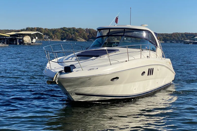The Image of 2006 Sea Ray 38 Sundancer yacht cruising on a serene lake under clear skies. - 0